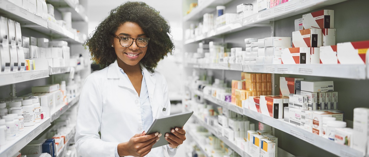 young female pharmacist in stock room holding tablet